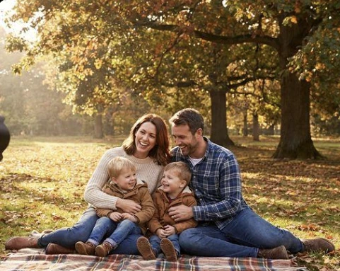 A family posing for an outdoor portrait among autumn trees